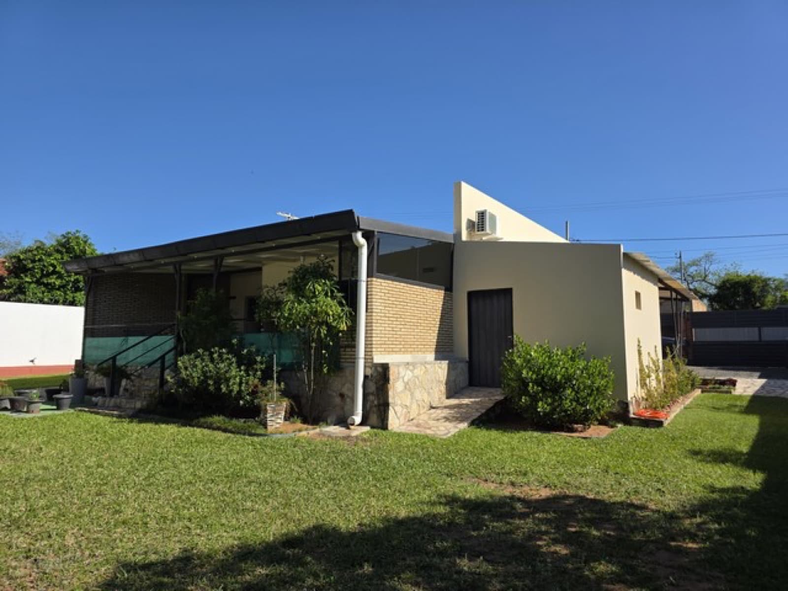 Haus mit überdachter Terrasse und Rasenfläche – Gartenseite